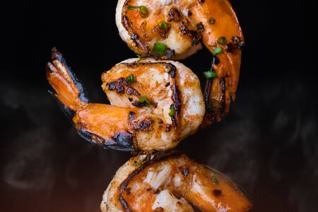 Skewer shrimps burnt grilled with spice seasoning with dark background.の写真素材