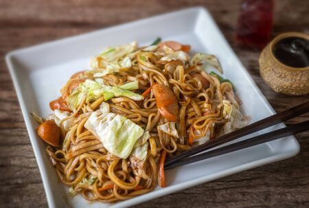 Yakisoba with sausage Japanese style fried noodle with sweet sauce in white plate with low sun lighting.の写真素材