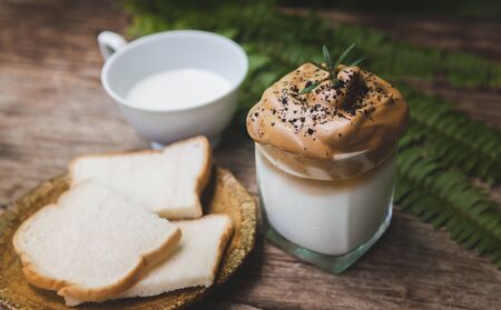 Dalgona coffee trendy Korean style on wooden plate with garden outdoor sun lighting.の写真素材