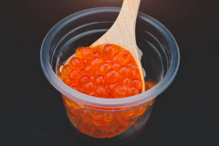 Salmon roe in wooden spoon with black background.の写真素材