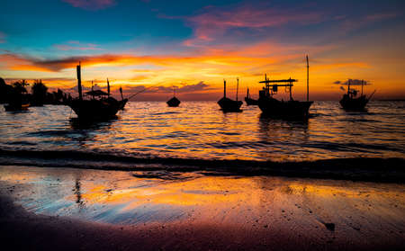Silhouette of fishery wooden boat with warm and sunset low lighting dark shadow view.の写真素材