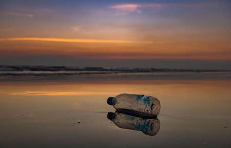 Plastic bottle on the beach with outdoor sun set low lighting and dark shadow.の写真素材