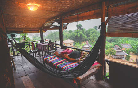 Relax hammock and bed with nature view from wooden balcony in low lighting and dark shadow.の写真素材