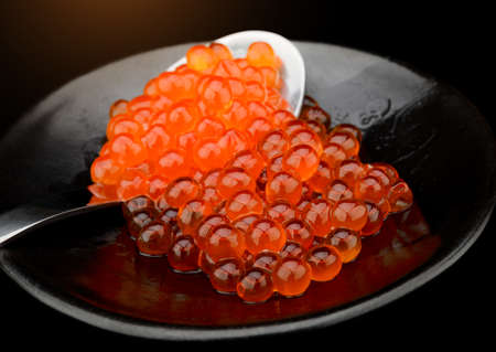 Salmon roe group in black plate with dark background.の写真素材