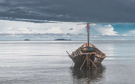 Fishery wooden boats with outdoor sun lighting and dark cloud sky.