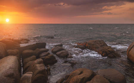 The rock in the sea with dark cloud sky in sunset time.の写真素材