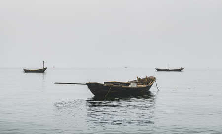 Wooden fishery boats in the sea with fog Weather and low lighting.の写真素材