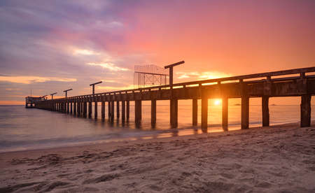 Long sea bridge in the sunset time with warm low lighting and dark shadow.の写真素材