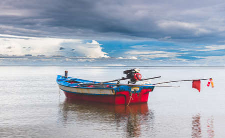 Fishery wooden boats with outdoor sun lighting and dark cloud sky.の写真素材