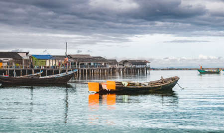 Fishery wooden boats with outdoor sun lighting and dark cloud sky.の写真素材