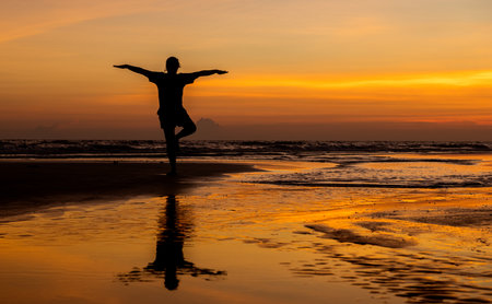 Silhouette relaxation woman on the beach with outdoor sunset and clouds warm lighting.の写真素材