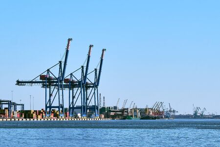 View of port cranes, loading bridges and container terminal. Sea trade, transportation, commerce and...