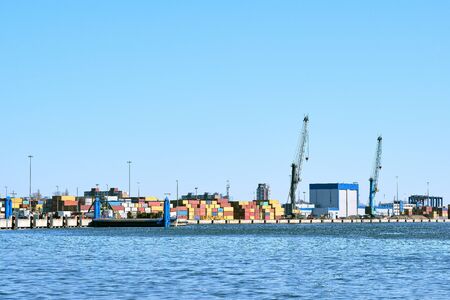View of port cranes, loading bridges and container terminal on clear sunny day and cloudless sky....