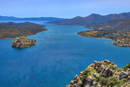 View of harbor between Spinalonga island and peninsula, known as Kalydon, and Plaka village from...