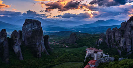 Sunset view of Meteora valley rocky hills and Moni Agias Varvaras Roussanou nunnery with clouds in colorful sky. Greeceの写真素材