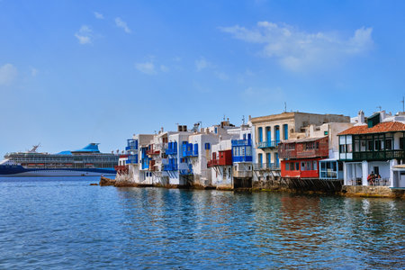 Beautiful Little Venice in Mykonos, Greece. Romantic neighborhood with whitewashed bars, cafes, restaurants. Giant cruise liner pass. Summer day.の写真素材