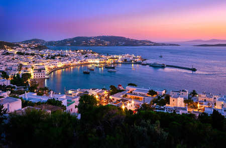 Colorful view after sunset over town of Mykonos, Cyclades, Greece, harbor and port, cruises, ship, whitewashed houses. Colorful town lights up.の写真素材