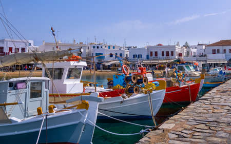 Beautiful summer day , marina of Greek island. Fishing boats moored at jetty. Mykonos, Cyclades, Greece. Whitewashed houses. Mediterranean lifestyle.の写真素材