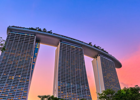 Rear view upshot of part Marina Bay Sands hotel and casino against colorful tropical sunset, Singapore. Iconic tourist attraction, luxury vacationsのeditorial素材