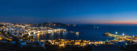 Beautiful night panorama of Mykonos, Greece, ships, port, whitewashed houses. Town lights up. Vacations, leisure, nightlife, Mediterranean lifestyleの写真素材