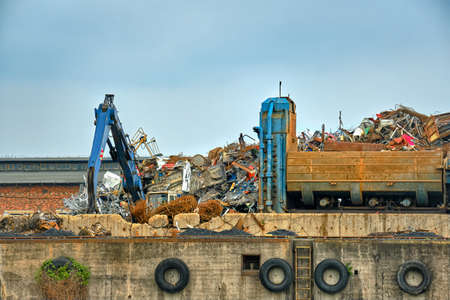 Backhoe loader and big construction debris in river port in overcast day.
