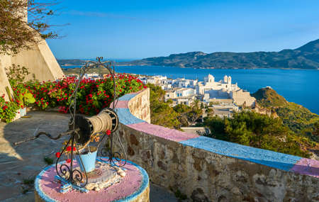 Colorful view on traditional Greek town by sea from decorated terrace with rich red cranesbills. White Orthodox Greek church, Plaka, Milos, Greeceの写真素材