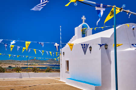 White Greek Orthodox chapel or church on top of hill against clear blue sky on sunny day, decorated Greek national, Greek Orthodox flag. Milos, Greeceの写真素材