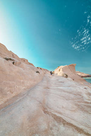 White rocks of Sarakiniko beach, Aegean sea, Milos island , Greece. Lonely stranger, empty cliffs, summer sunshine, lunar landscape, sky, cloudsの写真素材