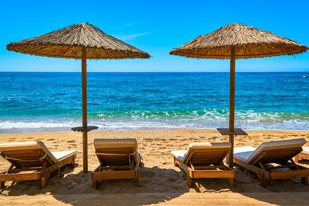 Two sun umbrellas and four sunbeds ready for tourists on sandy beach. Summer sunshine, vacations, sea, beach, sand, sunbathing, swimming.の写真素材