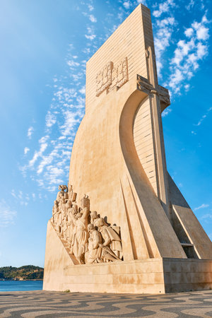 Monument to Discoveries or Padrao dos Descobrimentos to Age of Discovery shaped as ship and sword with statues of Prince Henry the Navigator and great people of Portuguese seafarers history, Lisbon, Portugal, at clear blue sky and sun rays on dayの写真素材