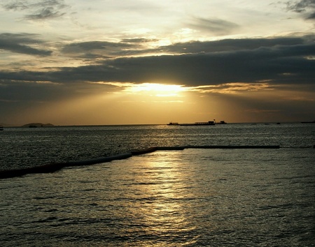 Ray of light in the cloudy sky at the sunset reflection on calm sea wave.の素材