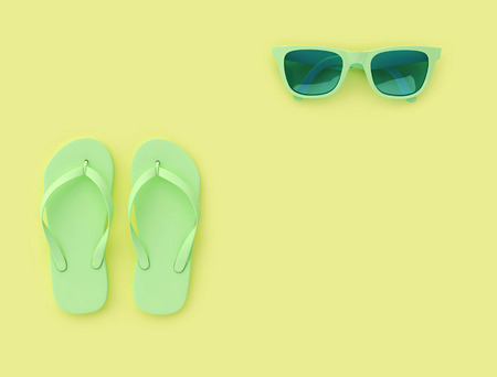 Light green flip flops and sunglasses on yellow background with copy space, summer vacation concept. 3D renderingの写真素材