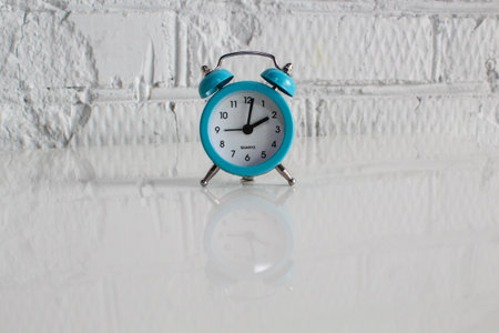 Close-up of blue Table Alarm Clock with bells on white table and white cement wall background. time concept.の写真素材