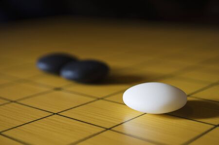 Closeup shot of a white and two black go stones on the goban  Go is an ancient traditional Asian board game  Shallow depth of field の写真素材