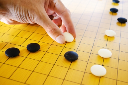 A male hand places a go stone on the board in a game of go の写真素材