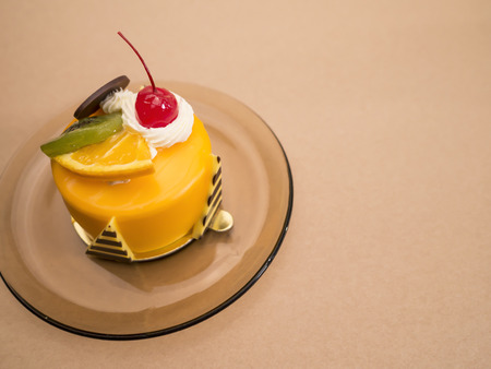 One orange cake with red cherry, Kiwi and Chocolate on dish. (Selective focus with red cherry)の写真素材