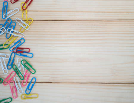 Colorful paper clip on wood background / texture
