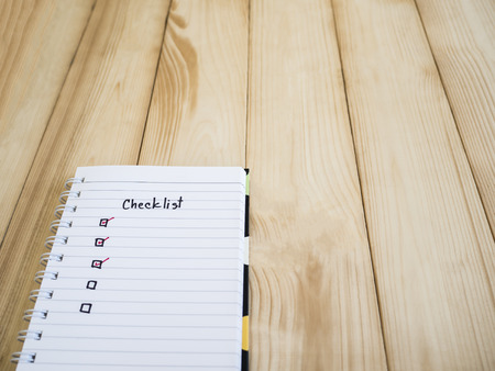 Checklist on notebook page with wood backgroundの写真素材
