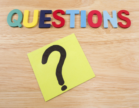 Word spelling Questions and question mark with wood background