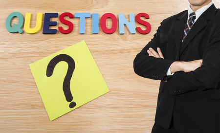 One business man wear black suit stand on Questions background (Business Concept)