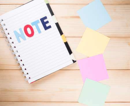 Blank notebook and colorful note paper on wood background