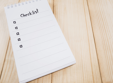 Checklist on notebook page with wood backgroundの写真素材
