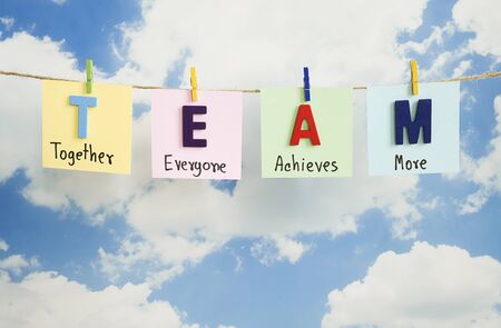 Word spelling "Team" hang with rope on blue sky background (Business concept)の写真素材