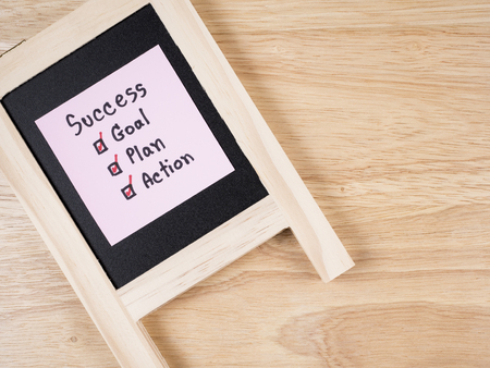 Handwriting word Success, Goal, Plan, Action on black board with wood background (Business concept)