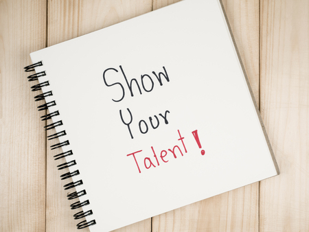 Handwriting Show Your Talent on blank notebook with wood background. (Business concept)の写真素材