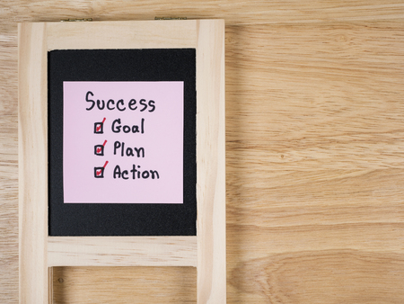 Handwriting word Success, Goal, Plan, Action on black board with wood background (Business concept)