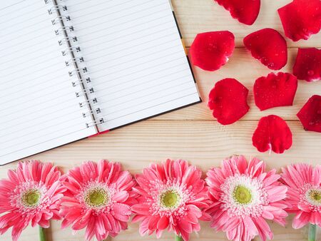 Notebook, red rose and pink flower on wood backgroundの写真素材