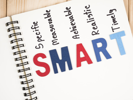 SMART Goals in notebook and pen on wood background (Business Concept)の写真素材