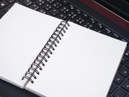 White blank notebook on laptop keyboard (Selective Focus)