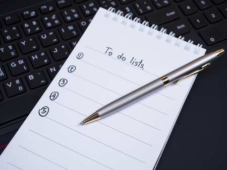 Pen put on to do list notebook with laptop key board background (Selective Focus)の写真素材